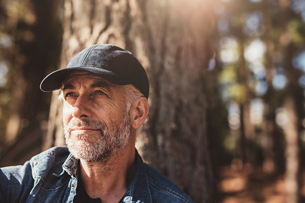 man sitting outside in the woods thinking