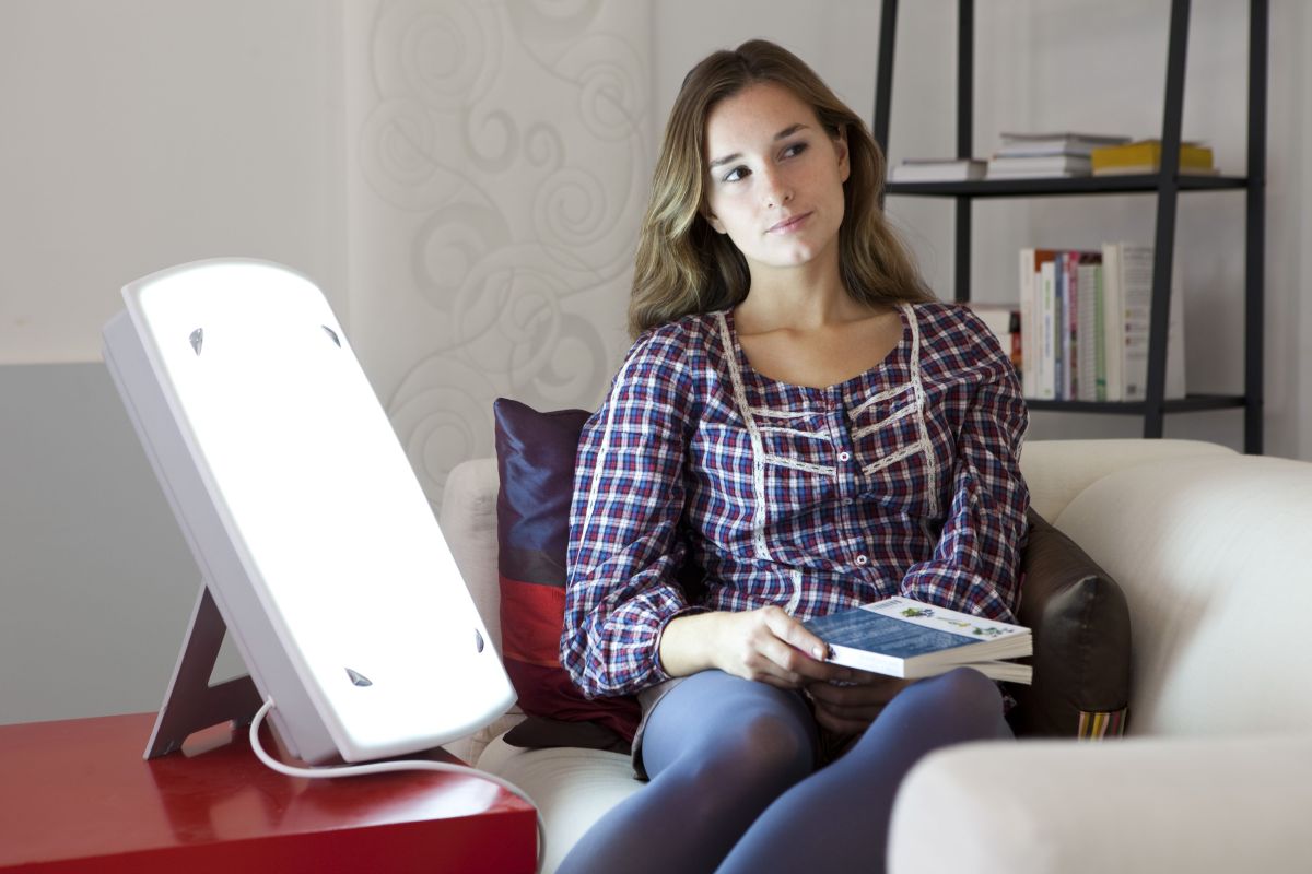 Woman sitting next to light therapy lamp