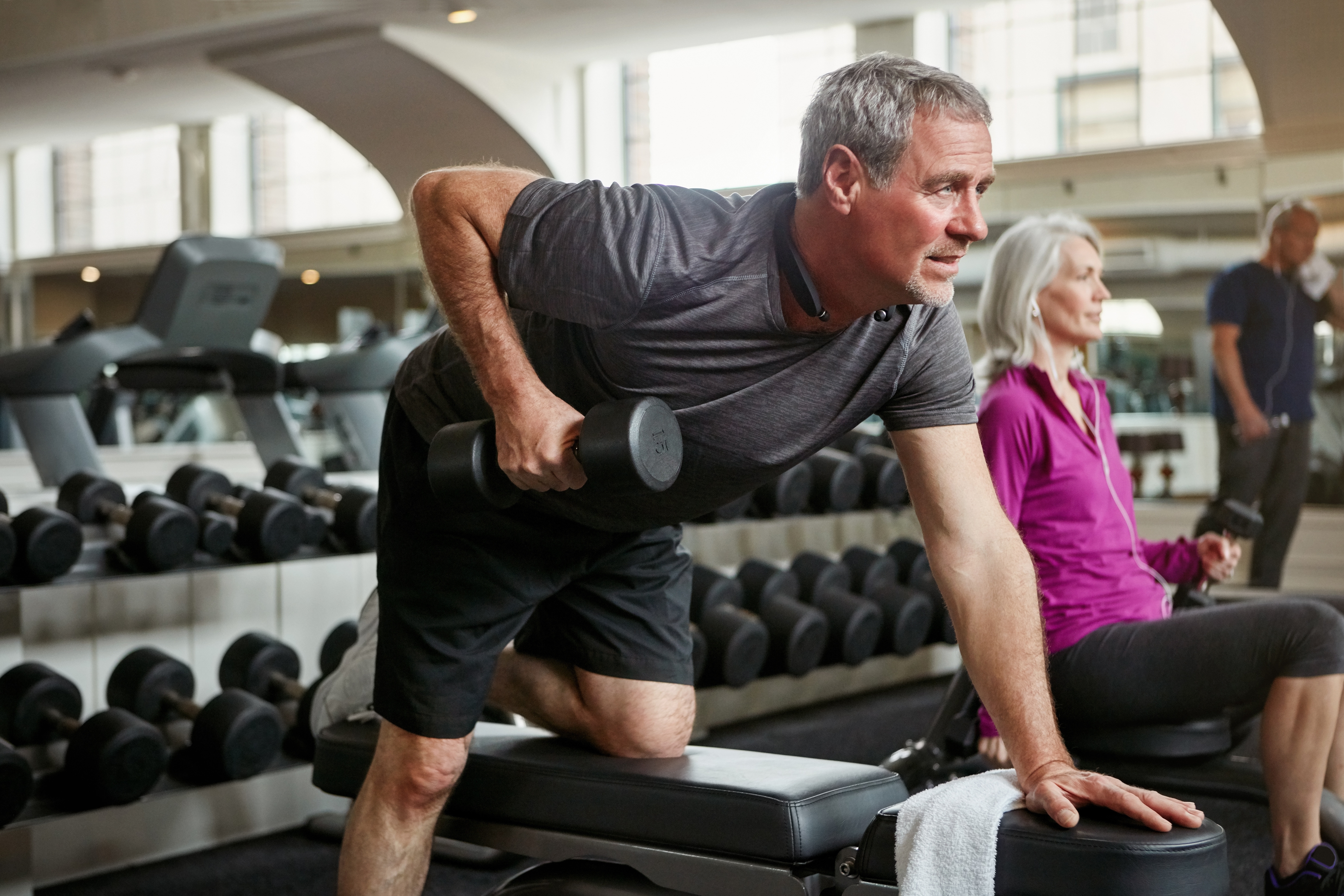 Senior man and woman strength training with weights at the gym