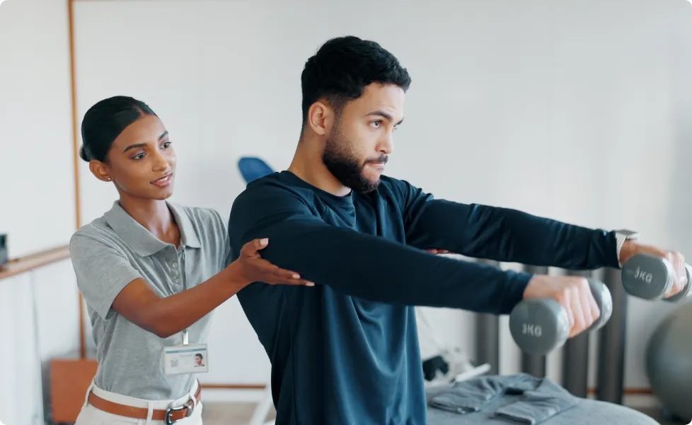 A physical therapist helping a patient with dumbbell exercises.