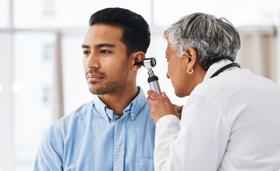 A physician performing an ear examination on a patient.
