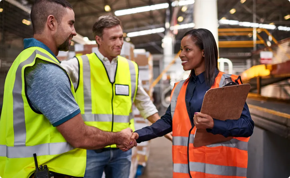 A supervisor shaking hands with a worker in a distribution center.